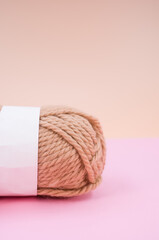 Vertical shot of isolated soft beige yarn ball on an pastel pink background