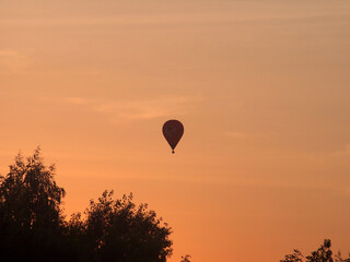 Balloons float across the sky against the background of sunset.