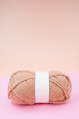 Vertical shot of isolated soft beige yarn ball on an pastel pink background