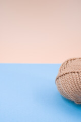 Vertical shot of isolated soft beige yarn ball on an pastel blue background