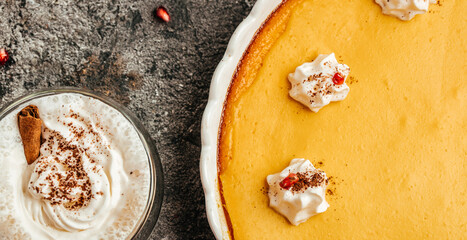 Traditional American pumpkin pie with cinnamon decorated with whipped cream and latte. Long banner format. top view