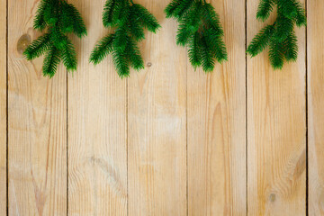 New Year and Christmas background. Artificial green spruce branches on rough light yellow wooden boards. Floor covering. Place for text and goods, copy space