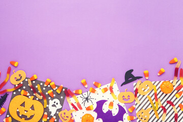 Fototapeta na wymiar Halloween candies with paper pumpkins, ghost and spider on purple background