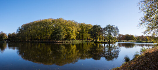 Fototapeta premium Trees and channels on the island Drottningholm an colorful autumn day in Stockholm,