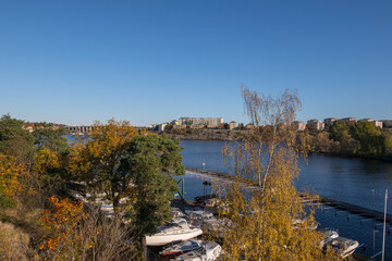 The skyline of the island Kungsholmen and piers with boats at the island Essingen an colorful autumn day in Stockholm