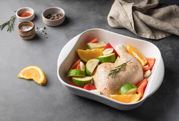 Raw chicken meat with vegetables, oranges and spices in pan on kitchen counter. healthy diet lunch. side view