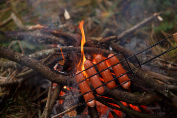 Sausages are fried on a wire rack and over a fire.