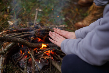 A man warms his hands by the fire.