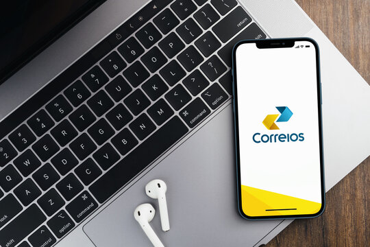 Correios do Brasil (Post office Brazil) app on the smartphone screen on wooden background with a computer beside it. Rio de Janeiro, RJ, Brazil. October 2021