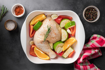 Raw chicken meat with vegetables, oranges and spices in a ceramic pan. Healthy festive food concept. top view