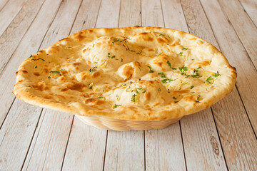Garlic naan without crumb cooked in a Hindu restaurant on wooden table