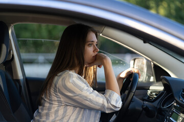 Fototapeta na wymiar Drunk girl driving car. Unhappy young female sit on driver seat suffering from headache or handover. Depressed tired woman in vehicle. Sleepy exhausted lady in auto in traffic jam looking frustrated