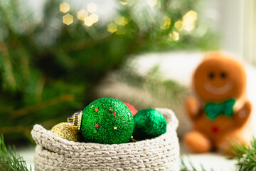 Merry Christmas and Happy New Year. A green Christmas ball in a light crocheted basket on a blurry shiny background.