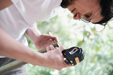 young adult latin man taking measurements with a tape measure in a bamboo