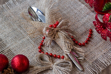 Elegant cutlery set,wrapped in jute napkin,on burlap surface with christmas decorations.Christmas or new year concept
