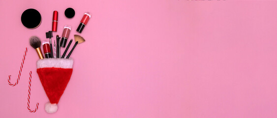 Happy New Year 2022. Cosmetics and Christmas canes in a Santa Claus hat on a pink background. the concept of a makeup artist. it's a postcard. Copy space. Banner.