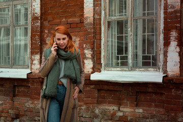 Redhead woman using phone for call outdoors in city