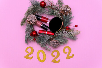 Happy New Year 2022. fir branches and cosmetics on a pink background. Cosmetics inside a Christmas...