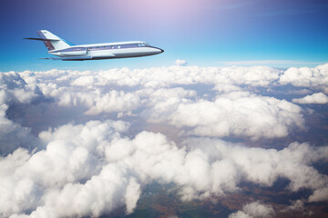 Naklejka na ściany i meble Business jet airplane fly above clouds in the sky
