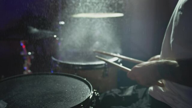 The drummer hits the wet drum cymbal with his drumstick and the water splashes in slow motion. In the recording studio of musical instruments. Knocks and beats, Repetition of rock music band.