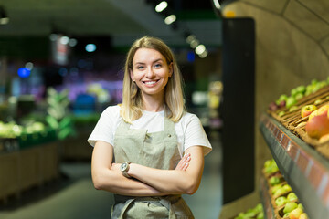 Portrait young woman worker seller in a Vegetable section supermarket standing in arms crossed....