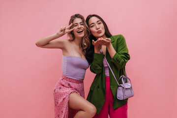 Beautiful young ladies of different nationalities blow kisses into lens on pink background....