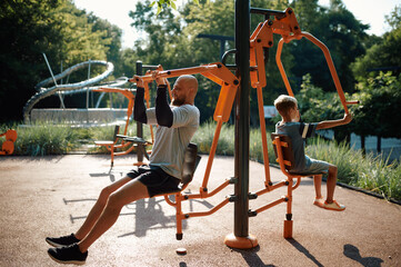 Father and child on exercise machine, playground