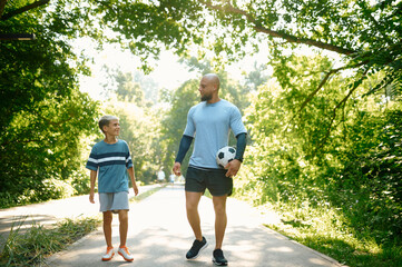 Father and son, football players on walking path