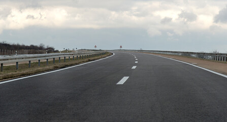 Road in the fog. Empty silent Freeway. Driving on an empty road. Empty asphalt road through the green field and clouds on rainstorm in rainy season. 
Open road ahead, endless road for concept.