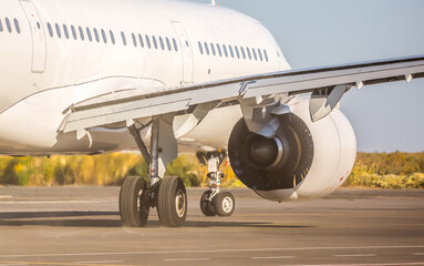 The plane is preparing to fly at the airport. Airplane on the runway at the airport. The turbine of the aircraft is warming up, the landing gear is preparing for flight. The plane flies in the sky.