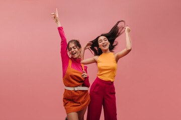 Two beautiful young girls from Ukraine and Asia dancing in pink background with place for text....