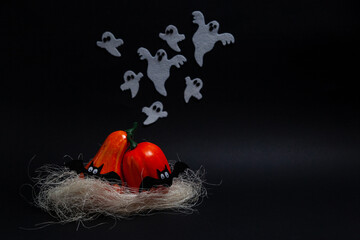 Obraz na płótnie Canvas Halloween, holidays and decoration concept - Two orange pumpkins of different sizes standing on a fake straw leaning over each other with flying ghosts and bats on a black background with copy space