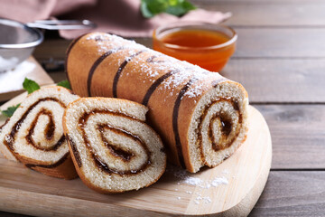 Tasty cake roll with jam on wooden table