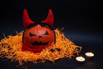 Holidays, Halloween and decoration concept - Jack-o-lantern pumpkin with devil horns, red bow tie,...