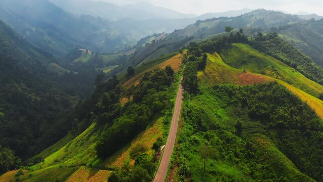 Aerial footage of winding road in rainy season on tropical rainforest mountain in Nan province, Thailand. 4K resolution drone footage top view.