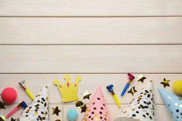 Flat lay composition with party hats and other festive items on white wooden background. Space for text