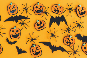 Happy Halloween. Pumpkins jack o lantern, spiders and bats flat lay on orange background. Halloween decorations layout on orange paper. Halloween background. Festive pattern