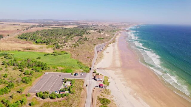 Aerial View of Praia de Sao Torpes and Praia de Morgavel Beach in 4K. Beautiful Portuguese coastal beaches with a huge parking spot filmed from above during a windy sunny day.