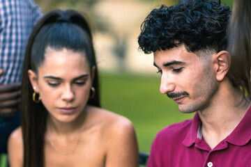 Two young people talking surrounded by other people in a park