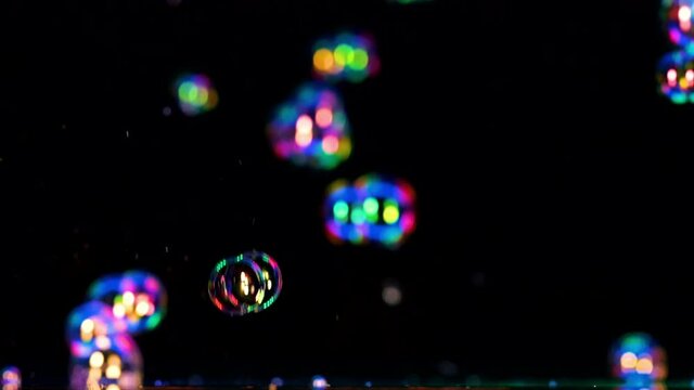 The colorful soap bubbles flying on a black background. slow motion