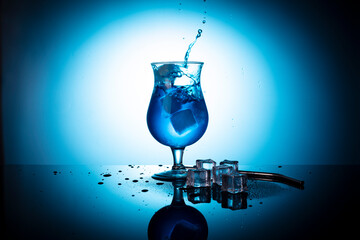 blue coctail splash. blue coctail drink with ice cubs. Blue lagoon non-alcoholiccoctail coctail on clean blue background