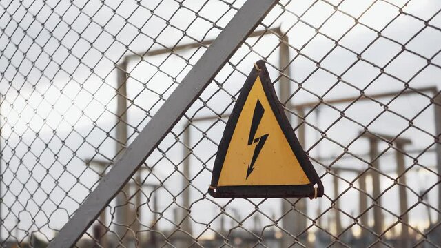 The sign Danger of electric shock on the fence from the grid near the substation. Yellow designation of high voltage