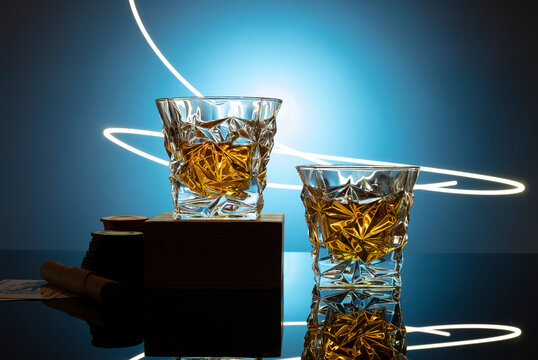 Cognac or brandy on a glossy table on an isolated blue background with a red flame