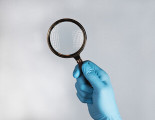 Hand in medical glove with magnifying lens, searching and examining diseases with glass.