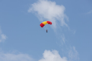 Skydiver under yellow and red parachute dome