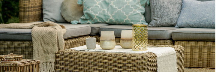 Lanterns, candles and vases on wicker coffee table in front of g