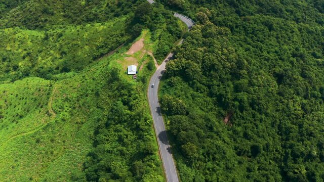Aerial footage of winding road in rainy season on tropical rainforest mountain in Nan province, Thailand. 4K resolution drone footage top view.