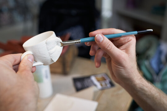 Keramikmalen mit Pinsel und wei&szlig;er Tasse