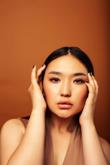 Fototapeta premium young pretty asian woman cheerful smiling posing on warm brown background, lifestyle people concept