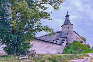 fragment of an old fortress wall with a corner watchtower in the ancient Russian city of Pskov - obrazy, fototapety, plakaty